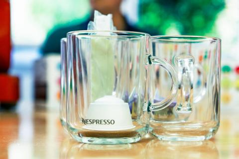 Une tasse en verre Nespresso aec une capsule blanche à l'intérieur