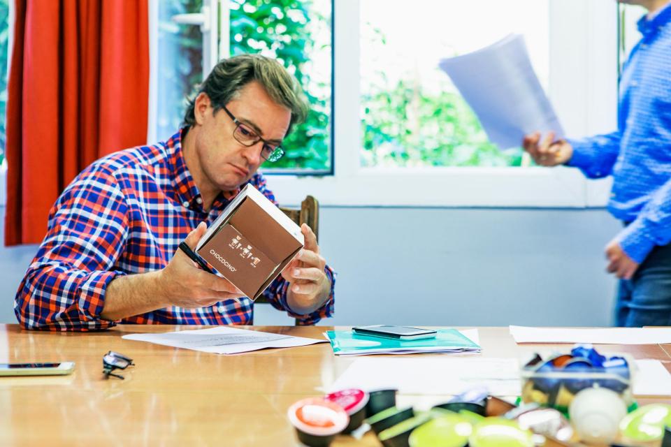 Un homme analyse une boite de capsule Nespresso